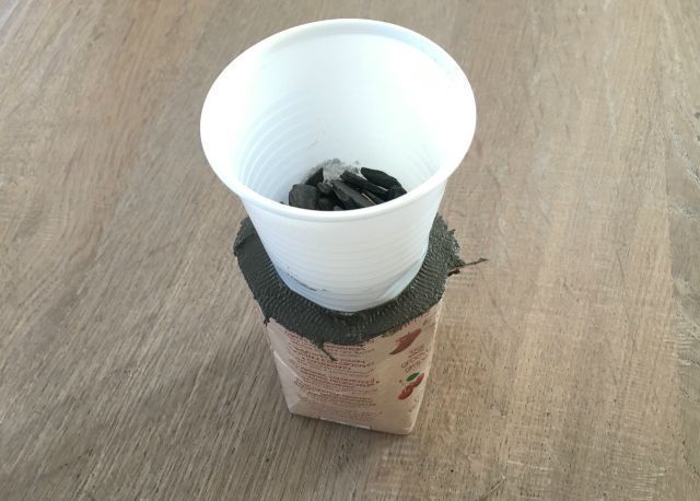 Then put your plastic cup on top of the cement in the package. This forms the hole for the tea light